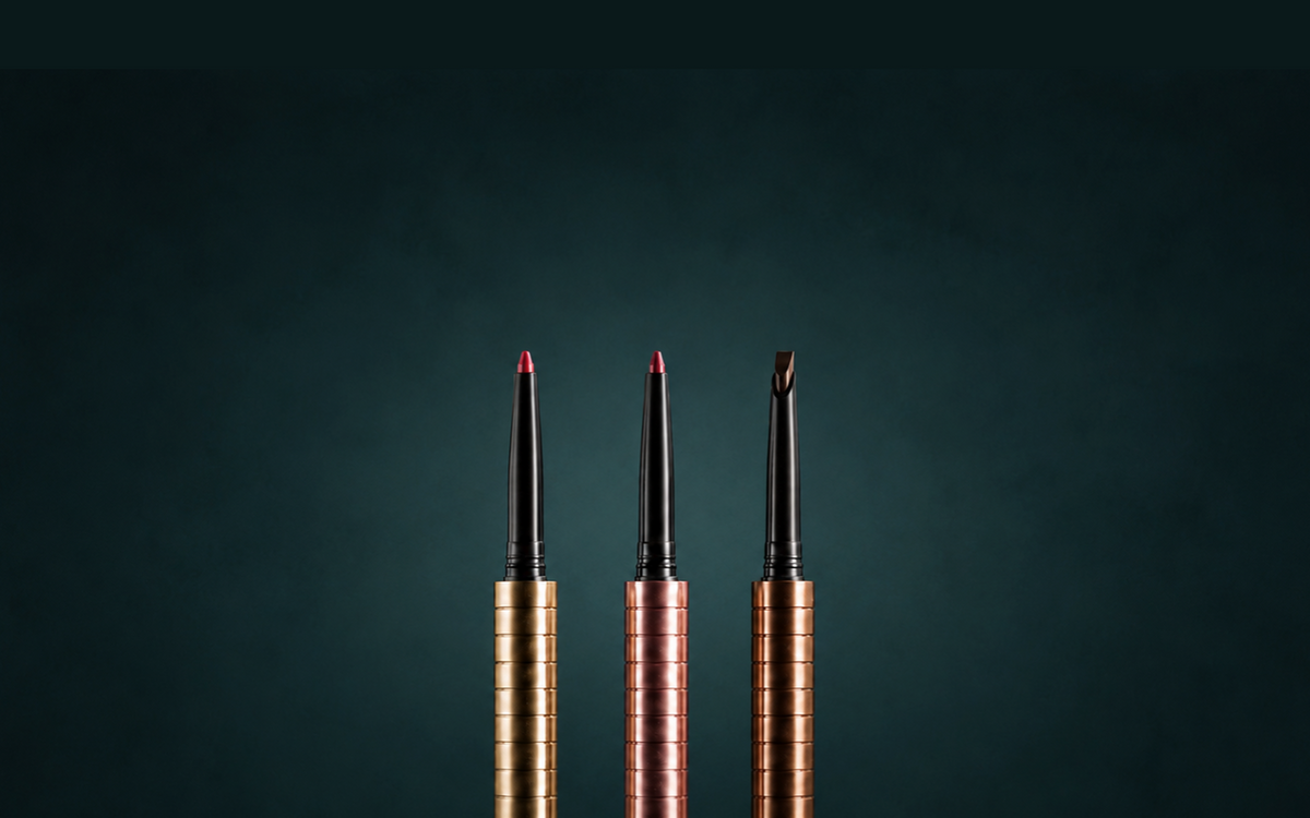 Three Karen Betts pens in gold-toned, rose and bronze finishes holding two lip cartridges and a brow cartridge