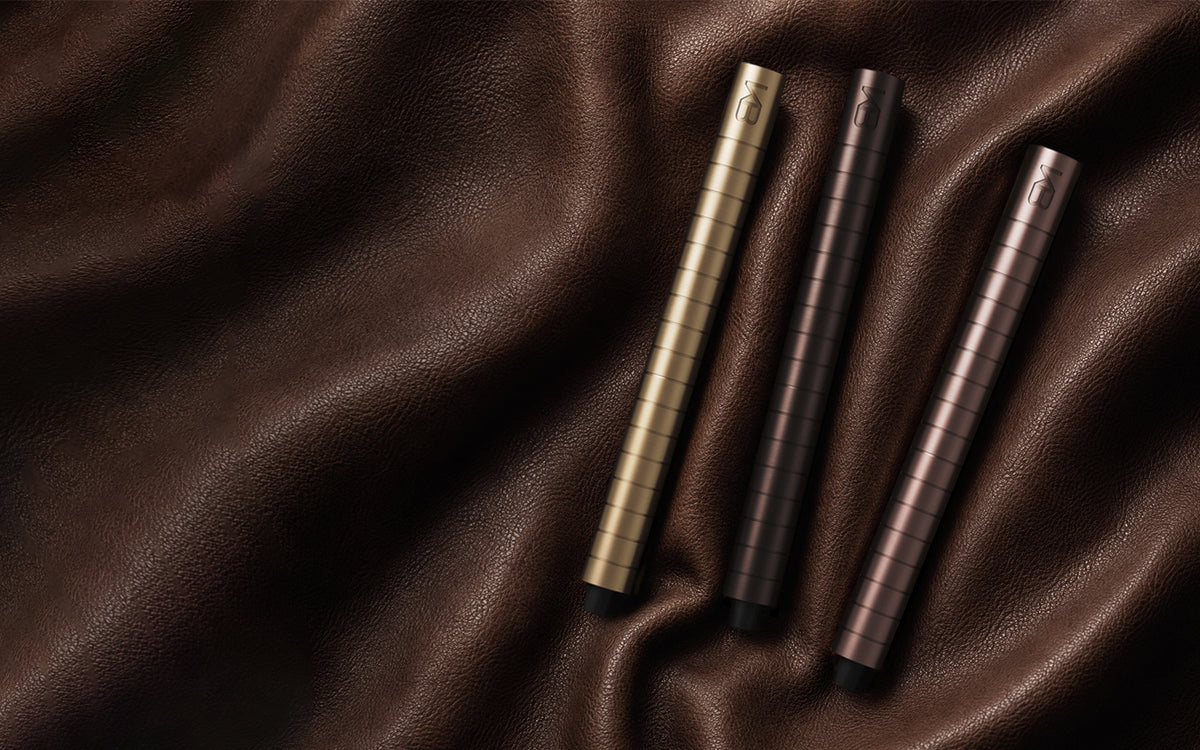 Three Karen Betts pens in Champagne, Chocolate and Rosewood on folds of brown leather