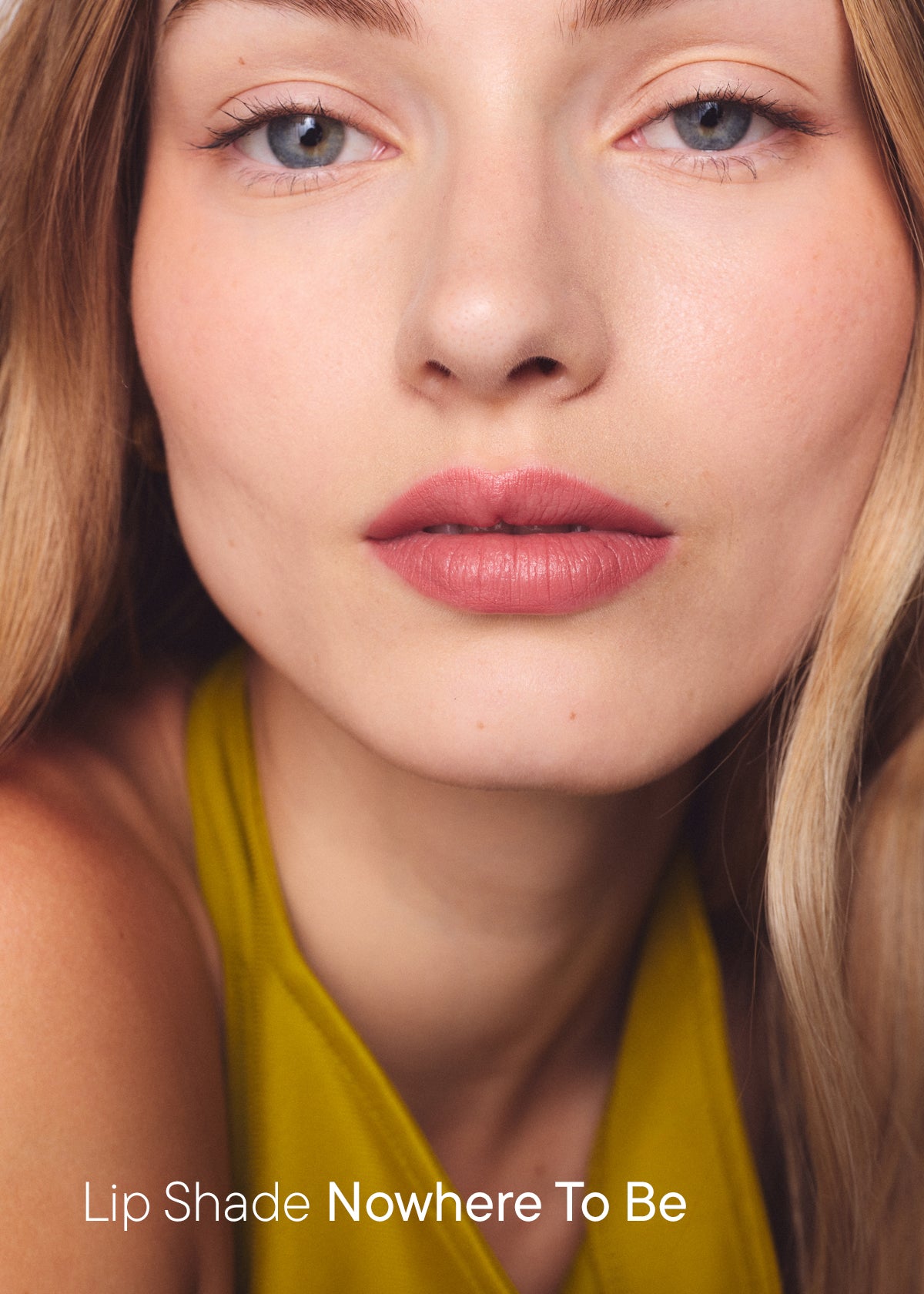Woman wearing the Nowhere To Be lip shade, a soft rosy mauve, with the text "Lip Shade Nowhere To Be"