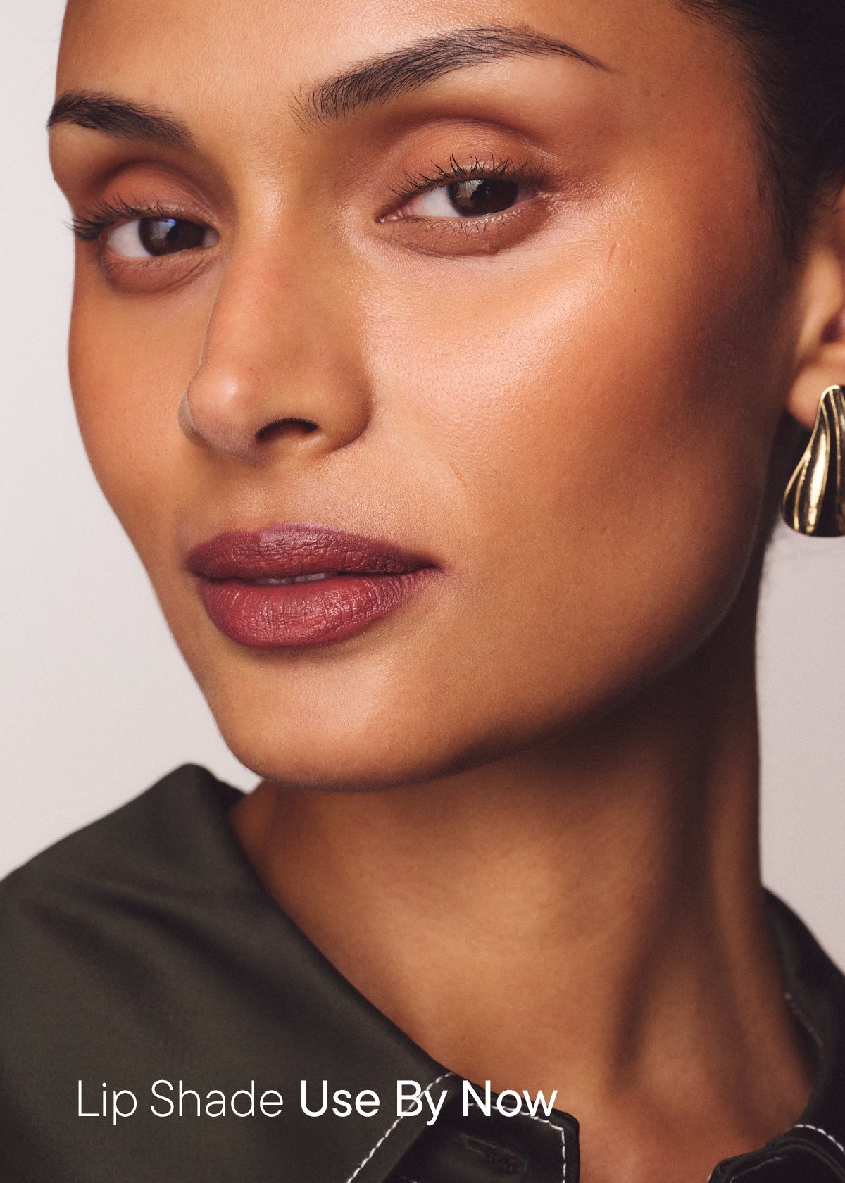 Woman wearing a muted rosy brown lip, with the text "Lip Shade Use By Now"