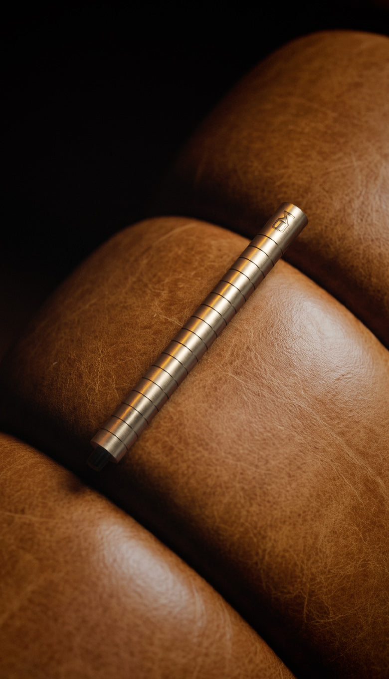 Karen Betts refillable pen in Champagne resting on tan leather