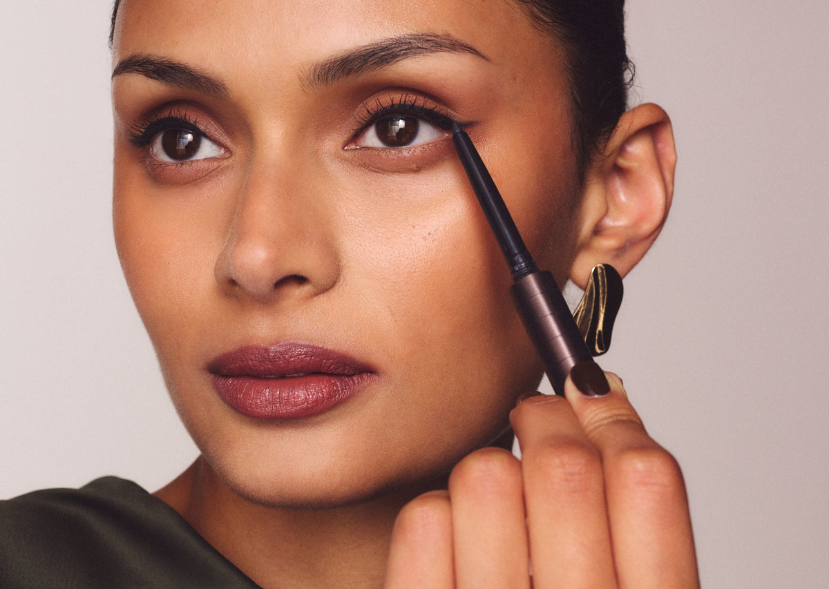 Woman applying eyeliner with the Chocolate Karen Betts pen, wearing a berry lip