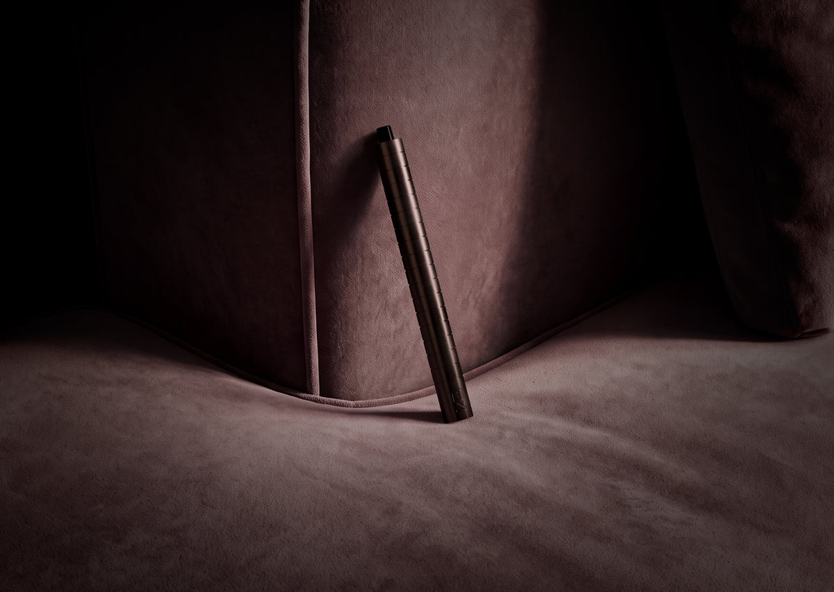 Karen Betts refillable pen in Chocolate propped against a plum velvet sofa