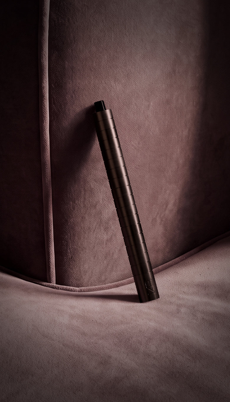 Karen Betts refillable pen in Chocolate propped against a plum velvet sofa