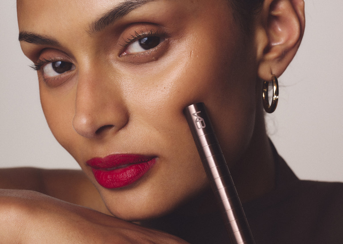 Woman wearing a red lip holding the Rosewood Karen Betts pen to her cheek