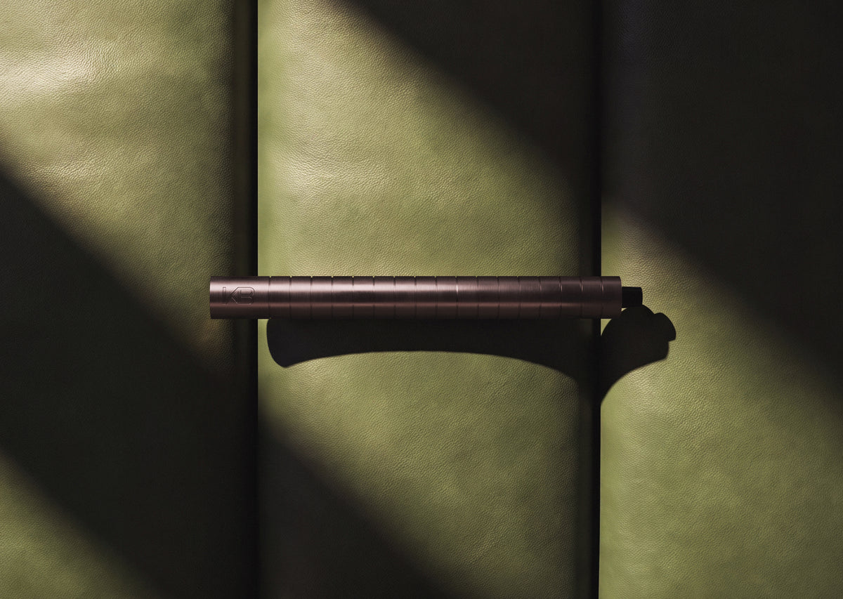 Karen Betts refillable pen in Rosewood lying across green leather in dramatic light