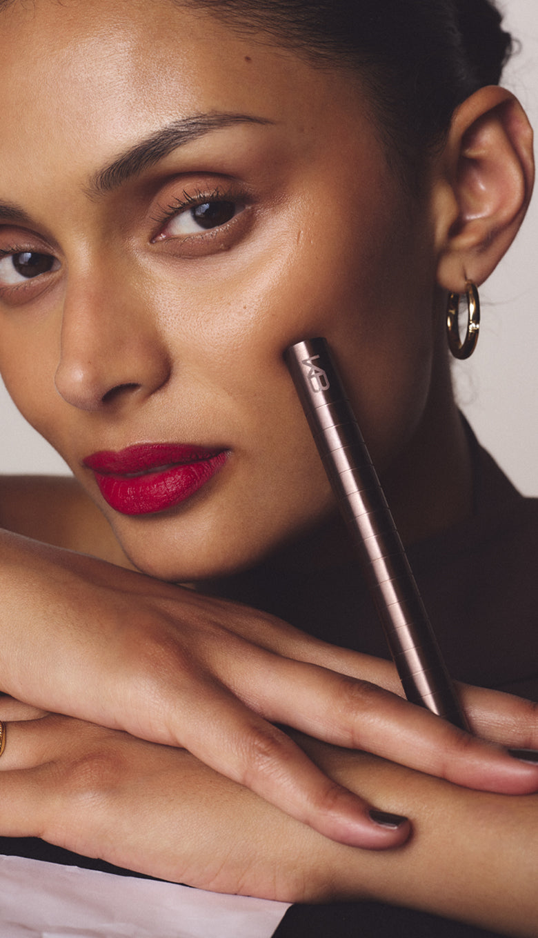 Woman wearing a red lip, holding the Rosewood Karen Betts pen to her cheek