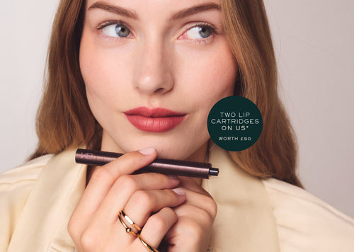Woman holding the Karen Betts pen under her chin, with a roundel reading "Two lip cartridges on us* – worth £50"