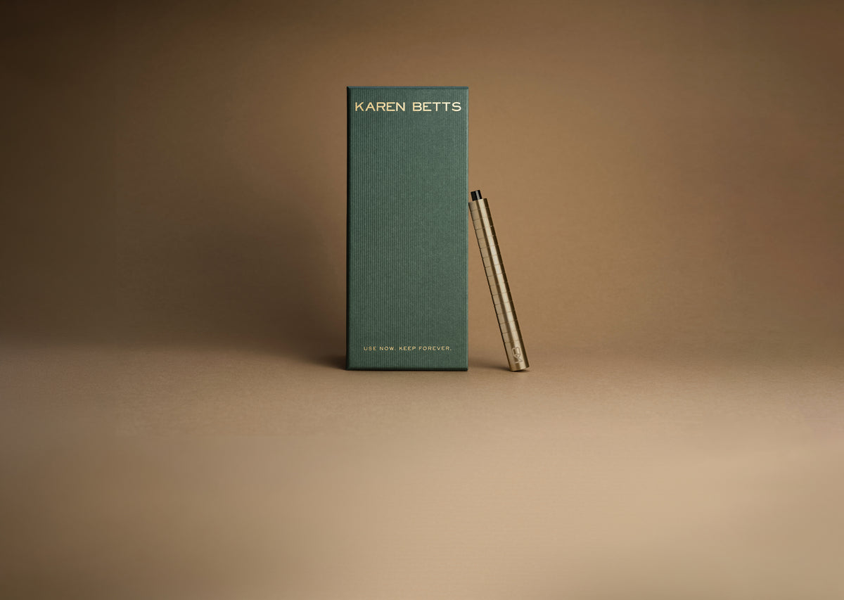Green Karen Betts pen box printed "Use now. Keep forever." with a gold-toned pen leaning against it
